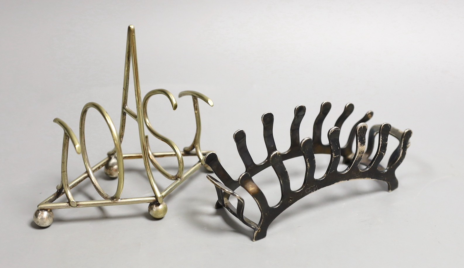A George VI silver demi-lune six division toast rack by Adie Brothers, Birmingham, 1949, 13.8cm, together with a novelty metal toast rack by Hukin and Heath, the divisions spelling the word 'Toast'.